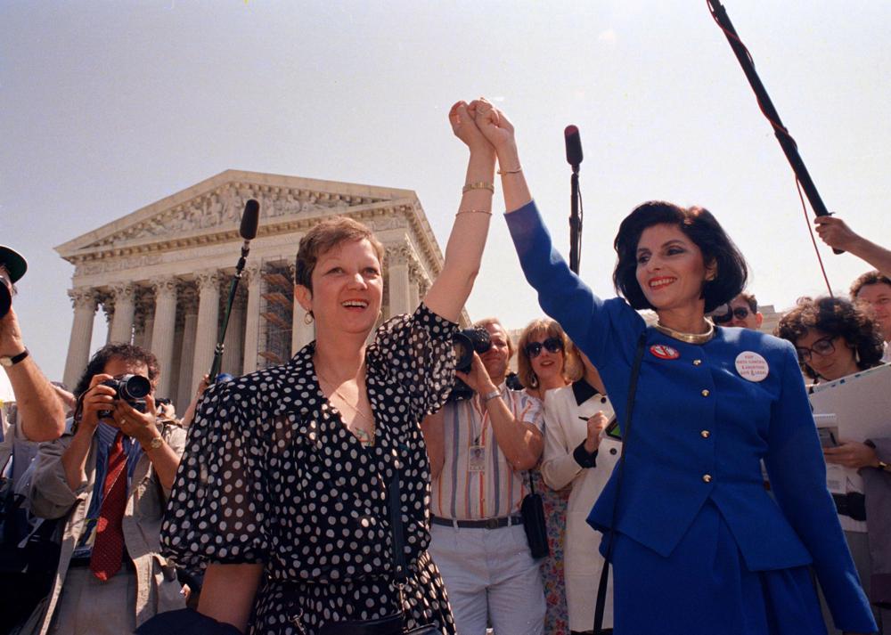 Jane Roe trong phi&ecirc;n t&ograve;a năm 1973 (tr&aacute;i) v&agrave; luật sư Gloria Allred của c&ocirc; nắm tay nhau khi họ rời t&ograve;a nh&agrave; T&ograve;a &aacute;n Tối cao ở Washington, ng&agrave;y 26/4/1989