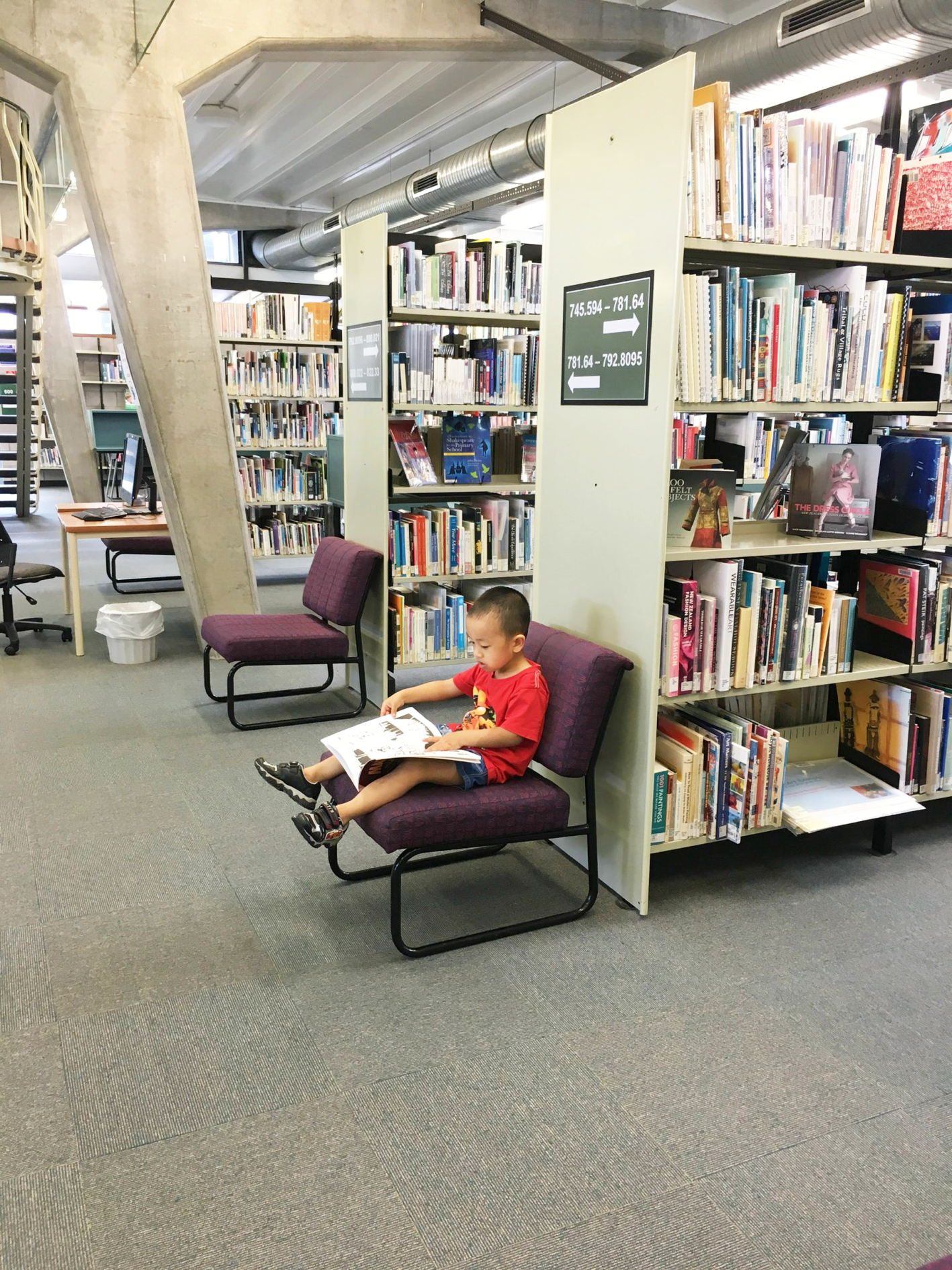 B&eacute; Minh Hải (năm tuổi) ngồi đọc s&aacute;ch ở thư viện Trường đại học Auckland trong khi đợi mẹ tra cứu t&agrave;i liệu