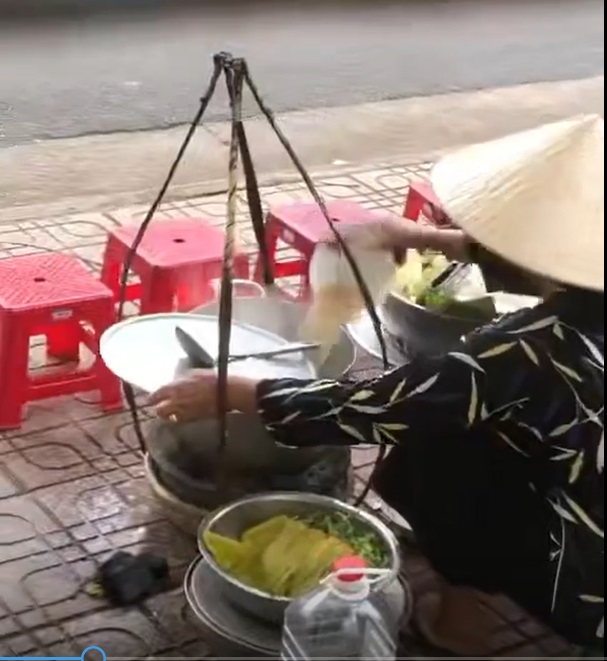 H&igrave;nh ảnh được cho l&agrave; người phụ nữ b&aacute;n h&agrave;ng rong đổ thức ăn thừa v&agrave;o nồi nước l&egrave;o - Ảnh cắt từ clip