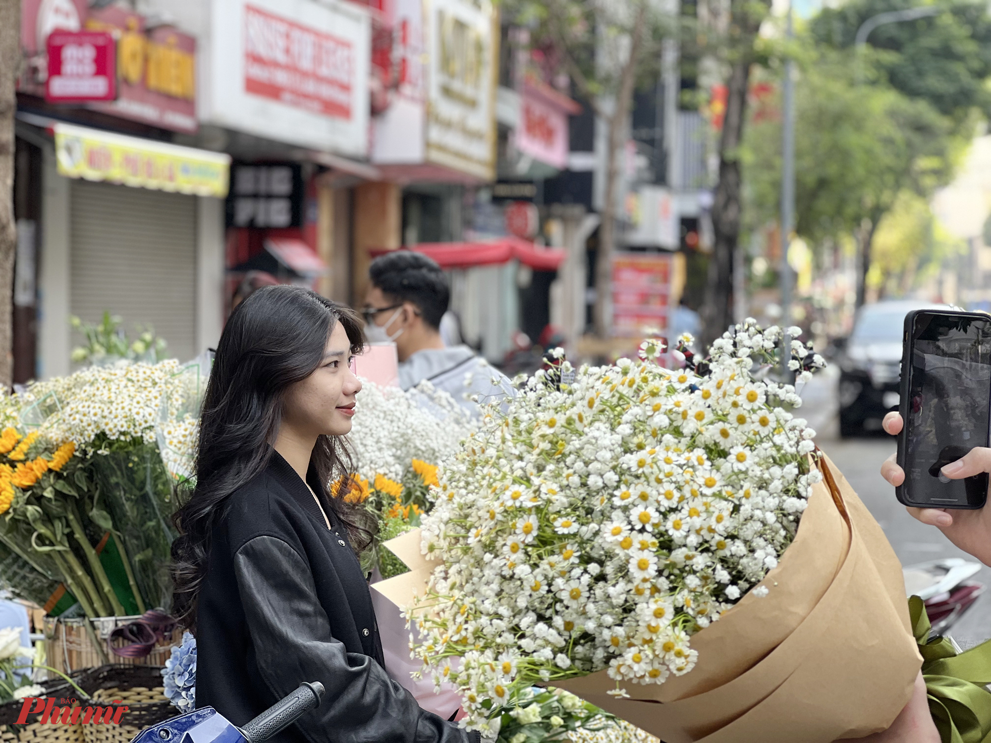 Sau khi mua hoa xong, nhiều bạn trẻ tranh thủ chụp ảnh check-in c&ugrave;ng xe hoa để lưu lại những khoảnh khắc đẹp dịp cuối tuần c&ugrave;ng bạn b&egrave;, người th&acirc;n. Khu vực n&agrave;y c&oacute; nhiều qu&aacute;n c&agrave; ph&ecirc;, gần đường đi bộ Nguyễn Huệ n&ecirc;n nhiều người mua hoa để l&agrave;m đạo cụ chụp ảnh.