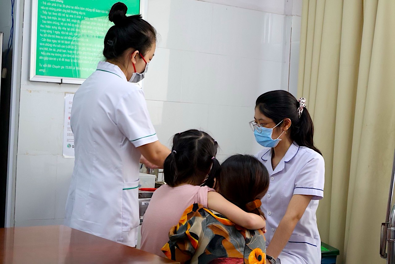 Phụ huynh đưa con đi ti&ecirc;m vaccine uốn v&aacute;n tại cơ sở ti&ecirc;m chủng tr&ecirc;n địa b&agrave;n TPHCM