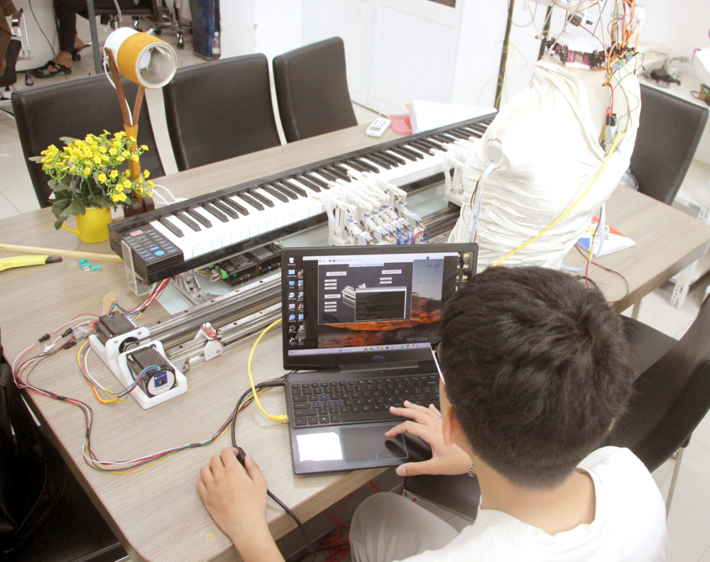 Sinh vi&ecirc;n năm thứ nhất ng&agrave;nh robot v&agrave; tr&iacute; tuệ nh&acirc;n tạo của Đại học Kinh tế TPHCM điều khiển robot chơi đ&agrave;n piano từ m&aacute;y t&iacute;nh - ẢNH: NGUYỄN LOAN