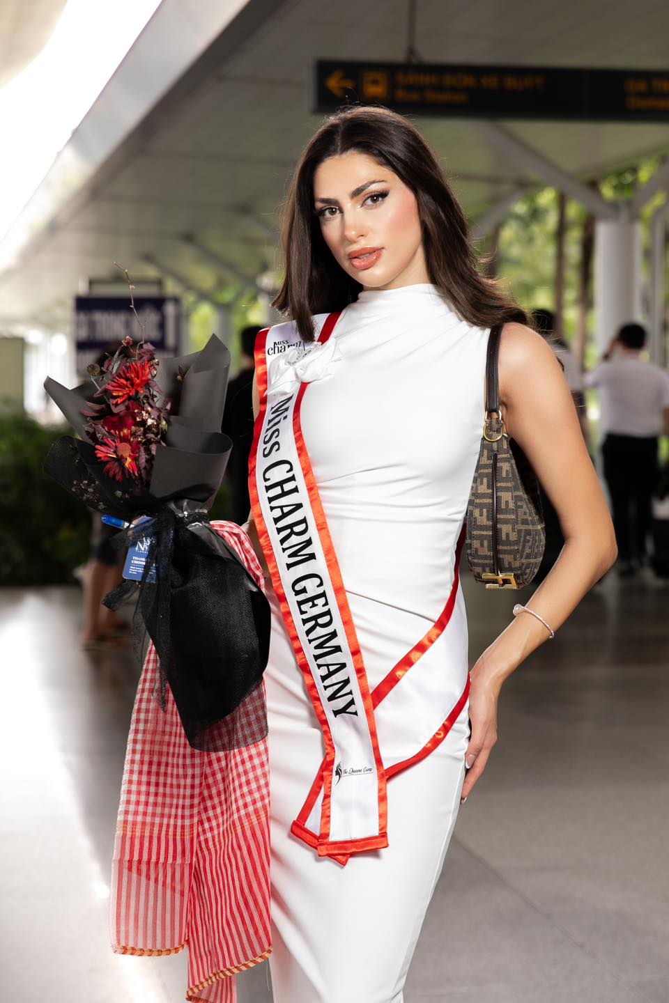 Maria Ignat l&agrave; th&iacute; sinh đến từ Đức, vừa c&oacute; mặt tại TPHCM để nhập cuộc. C&ocirc; chọn diện đầm trắng thanh lịch, nhưng vẫn kh&eacute;o leo khoe đường cong. Người đẹp th&iacute;ch th&uacute; khi vừa đến s&acirc;n bay T&acirc;n Sơn Nhất đ&atilde; được tặng khăn rằn. 