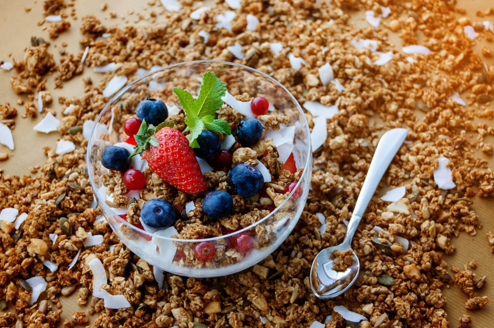 Sữa chua kh&ocirc;ng đường gi&agrave;u probiotics, tốt cho ti&ecirc;u h&oacute;a v&agrave; gi&uacute;p c&acirc;n bằng hệ vi sinh đường ruột, rất th&iacute;ch hợp cho những ai muốn ăn vặt m&agrave; lại sợ bị tăng c&acirc;n. Khi kết hợp c&ugrave;ng một ch&uacute;t granola tự l&agrave;m v&agrave; c&aacute;c loại tr&aacute;i c&acirc;y tươi như việt quất, d&acirc;u t&acirc;y hay chuối, bạn sẽ c&oacute; m&oacute;n ăn bổ dưỡng v&agrave; ngon miệng. Để c&oacute; thể tự l&agrave;m granola tại nh&agrave;, bạn c&oacute; thể nướng yến mạch với một ch&uacute;t mật ong, hạt hạnh nh&acirc;n v&agrave; quả &oacute;c ch&oacute;. Mỗi lần ăn, chỉ cần th&ecirc;m một ch&uacute;t granola v&agrave;o sữa chua l&agrave; bạn đ&atilde; c&oacute; một m&oacute;n ăn vặt tuyệt vời m&agrave; kh&ocirc;ng lo ảnh hưởng đến v&oacute;c d&aacute;ng.