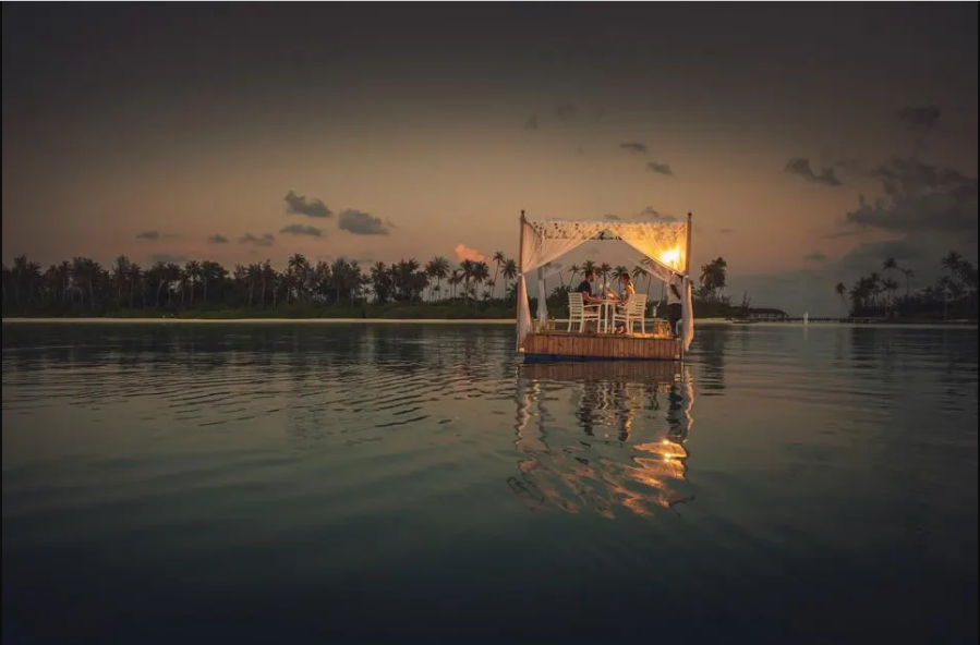 Bữa tối tr&ecirc;n b&egrave; nổi ở Maldives: Resort Sun Siyam Olhuveli c&oacute; phục vụ bữa ăn dưới bầu trời đầy sao giữa Ấn Độ Dương tr&ecirc;n một chiếc b&egrave;. Du kh&aacute;ch sẽ đi thuyền một đoạn ngắn v&agrave;o l&uacute;c ho&agrave;ng h&ocirc;n đến một b&egrave; nhỏ. B&agrave;n ăn được thắp s&aacute;ng bằng &aacute;nh đ&egrave;n v&agrave;ng v&agrave; &aacute;nh trăng lung linh c&ugrave;ng m&oacute;n khai vị, s&uacute;p, m&oacute;n ch&iacute;nh v&agrave; tr&aacute;ng miệng - Ảnh: Resort Sun Siyam