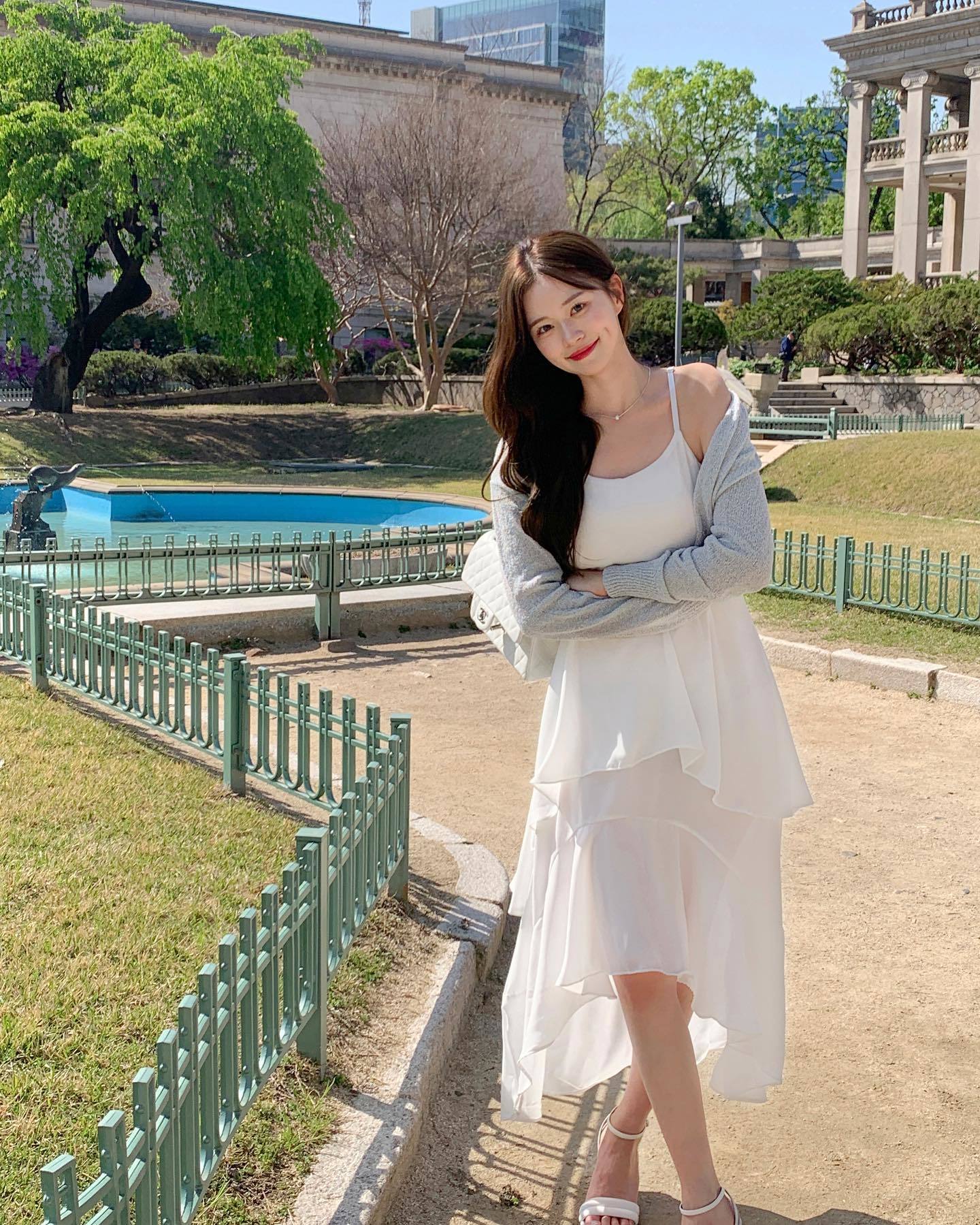 Sự kết hợp giữa v&aacute;y hai d&acirc;y trắng v&agrave; &aacute;o cardigan mỏng đ&atilde; tạo n&ecirc;n bộ trang phục nữ t&iacute;nh, bay bổng. Chị em n&ecirc;n chọn sandal m&agrave;u trung t&iacute;nh để c&oacute; được bộ trang phục h&agrave;i h&ograve;a, trang nh&atilde; nhưng kh&ocirc;ng k&eacute;m phần trẻ trung.