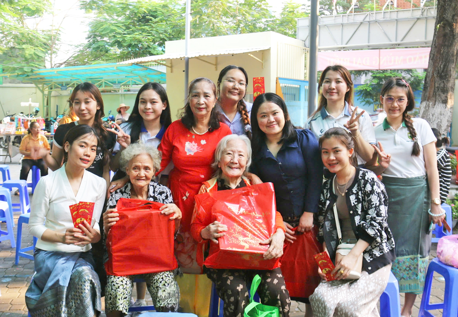 C&aacute;c sinh vi&ecirc;n L&agrave;o c&ugrave;ng m&aacute; Huệ (đứng, thứ ba từ tr&aacute;i sang) trao qu&agrave; tết cho phụ nữ kh&oacute; khăn