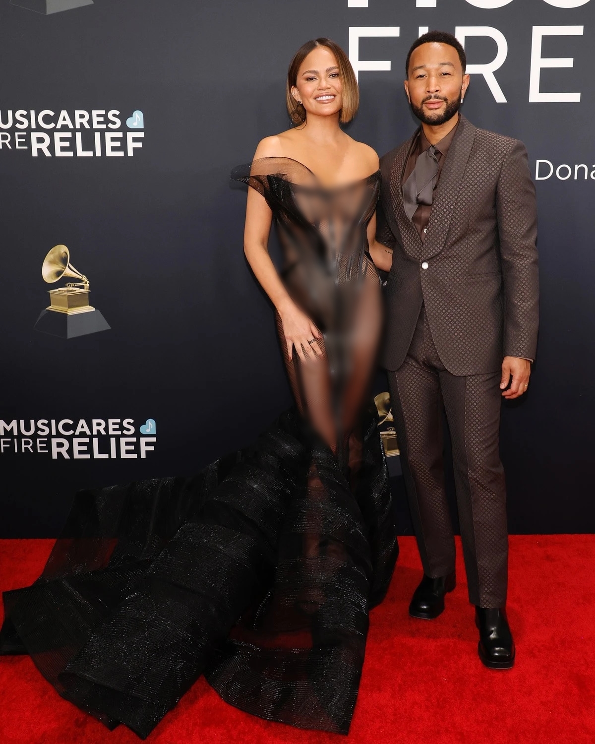 Ca sĩ John Legend lịch l&atilde;m trong bộ suit m&agrave;u n&acirc;u chocolate đậm, th&aacute;p t&ugrave;ng vợ - diễn vi&ecirc;n Chrissy Teigen. C&ocirc; diện bộ c&aacute;nh xuy&ecirc;n thấu, thiết kế cầu kỳ khoe d&aacute;ng.