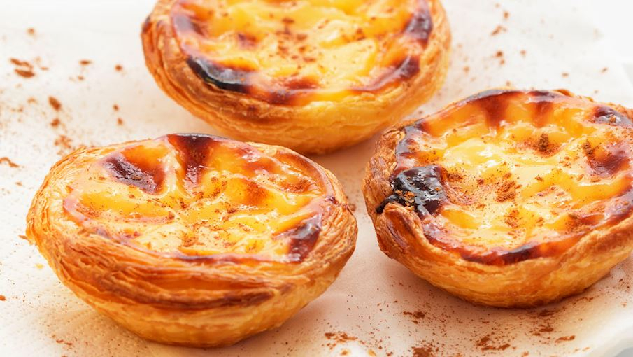Pastel de nata l&agrave; một loại b&aacute;nh tart nh&acirc;n kem trứng truyền thống, được y&ecirc;u th&iacute;ch tr&ecirc;n khắp thế giới. Để c&oacute; hương vị ho&agrave;n hảo nhất, phần nh&acirc;n kh&ocirc;ng n&ecirc;n qu&aacute; ngọt v&agrave; kh&ocirc;ng n&ecirc;n c&oacute; m&ugrave;i chanh hay vani. Thay v&agrave;o đ&oacute;, b&aacute;nh thường được rắc một ch&uacute;t bột quế v&agrave; l&yacute; tưởng nhất l&agrave; thưởng thức c&ugrave;ng một t&aacute;ch c&agrave; ph&ecirc;.  Ban đầu, m&oacute;n b&aacute;nh n&agrave;y được c&aacute;c tu sĩ v&agrave; nữ tu C&ocirc;ng gi&aacute;o tại tu viện Santa Maria de Bel&eacute;m ở Lisbon l&agrave;m ra từ trước thế kỷ 18. B&aacute;nh được chế biến từ l&ograve;ng đỏ trứng dư thừa, vốn được d&ugrave;ng để lọc rượu vang v&agrave; hồ cứng quần &aacute;o. Sau đ&oacute;, c&aacute;c tu sĩ đ&atilde; thỏa thuận với một tiệm b&aacute;nh gần đ&oacute; để b&aacute;n pastel de nata thương mại, v&agrave; m&oacute;n b&aacute;nh n&agrave;y nhanh ch&oacute;ng trở th&agrave;nh một th&agrave;nh c&ocirc;ng lớn.