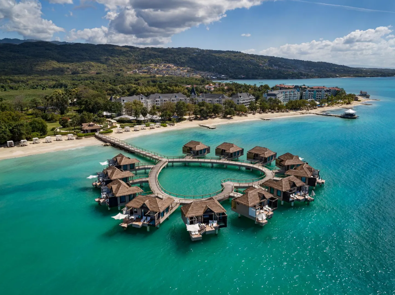 Resort Sandals South Coast ở Savanna-la-Mar, Jamaica. C&aacute;c cặp đ&ocirc;i sẽ c&oacute; kỳ nghi l&atilde;ng mạn trong c&aacute;c biệt thự tr&ecirc;n mặt nước của resort Sandals South Coast ở bờ biển ph&iacute;a nam của Jamaica. Biệt thực ở đ&acirc;y được xếp theo h&igrave;nh tr&aacute;i tim, c&oacute; lối đi ra biển để bơi; b&ecirc;n trong c&oacute; s&acirc;n hi&ecirc;n, bồn tắm v&agrave; c&oacute; dịch vụ quản gia. C&aacute;c cặp đ&ocirc;i th&iacute;ch nước c&oacute; thể tham gia lặn biển v&agrave; kh&aacute;m ph&aacute; c&aacute;c rạn san h&ocirc; gần đ&oacute;. Ảnh tr&ecirc;n: Khu biệt thự tr&ecirc;n mặt nước h&igrave;nh tr&aacute;i tim tại Sandals South Coast ở Jamaica.- Ảnh: Sandals