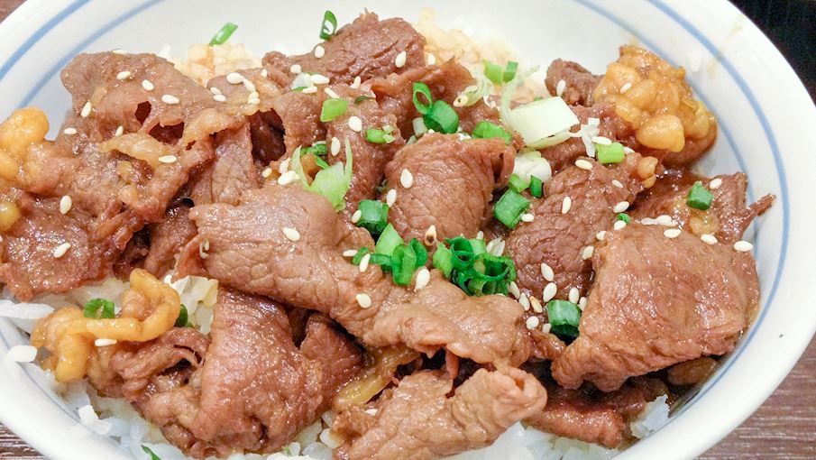  7/ Gyūdon l&agrave; một trong những m&oacute;n ăn nhanh phổ biến v&agrave; b&igrave;nh d&acirc;n nhất tại Nhật Bản. T&ecirc;n gọi của m&oacute;n ăn c&oacute; nghĩa l&agrave; b&aacute;t thịt b&ograve;, phản &aacute;nh đ&uacute;ng th&agrave;nh phần ch&iacute;nh của n&oacute;. Gyūdon bao gồm thịt b&ograve; th&aacute;i mỏng v&agrave; h&agrave;nh t&acirc;y, được nấu c&ugrave;ng hỗn hợp mirin, đường, rượu sake v&agrave; nước tương, tạo n&ecirc;n hương vị h&agrave;i h&ograve;a giữa vị mặn v&agrave; ngọt.Tại c&aacute;c nh&agrave; h&agrave;ng chuy&ecirc;n phục vụ gyūdon, c&ograve;n gọi l&agrave; gyūdon-ya, tr&ecirc;n b&agrave;n thường c&oacute; gừng đỏ ng&acirc;m v&agrave; ớt bột đỏ, gi&uacute;p thực kh&aacute;ch dễ d&agrave;ng điều chỉnh hương vị theo sở th&iacute;ch. Những qu&aacute;n ăn n&agrave;y l&agrave; điểm đến quen thuộc của sinh vi&ecirc;n, người lao động v&agrave; những ai muốn c&oacute; một bữa ăn nhanh gọn, ngon miệng với gi&aacute; cả hợp l&yacute;. Nhiều cửa h&agrave;ng gyūdon thậm ch&iacute; mở cửa 24/7 để phục vụ kh&aacute;ch bất cứ l&uacute;c n&agrave;o trong ng&agrave;y.