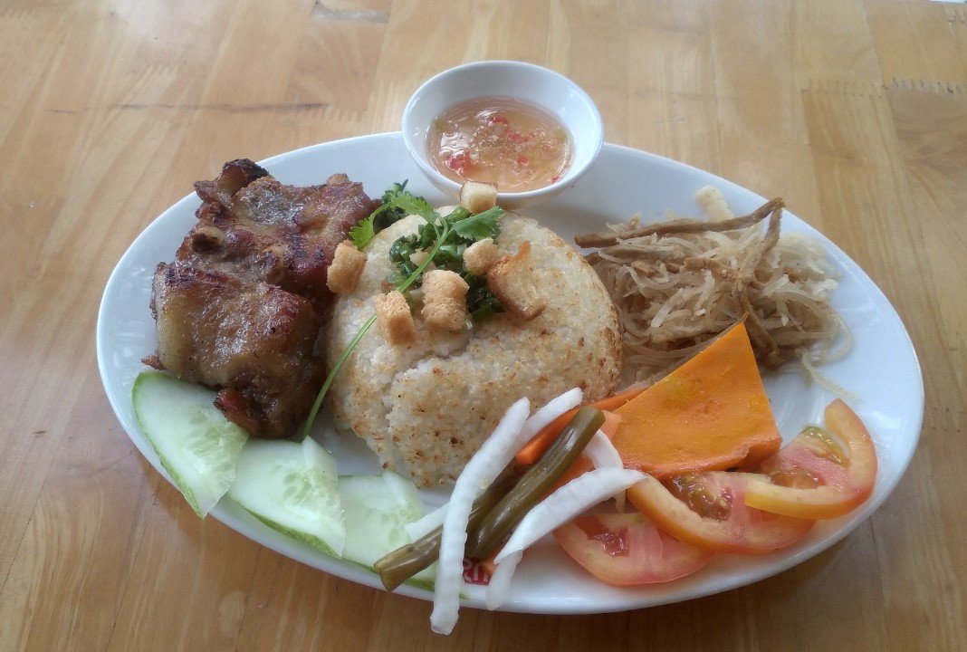 Cơm tấm sườn l&agrave; một m&oacute;n ăn phổ biến ở miền Nam. Thịt heo được ướp với gia vị v&agrave; nướng l&ecirc;n. Dưa leo, c&agrave; chua, c&agrave; rốt ng&acirc;m chua, miếng thịt nướng thơm ngon để l&ecirc;n dĩa cơm tấm, chan nước mắm sền sệt tạo n&ecirc;n m&oacute;n ăn rất ngon. Ảnh: Cơm tấm được biến tấu c&oacute; lớp cơm ch&aacute;y b&ecirc;n tr&ecirc;n.