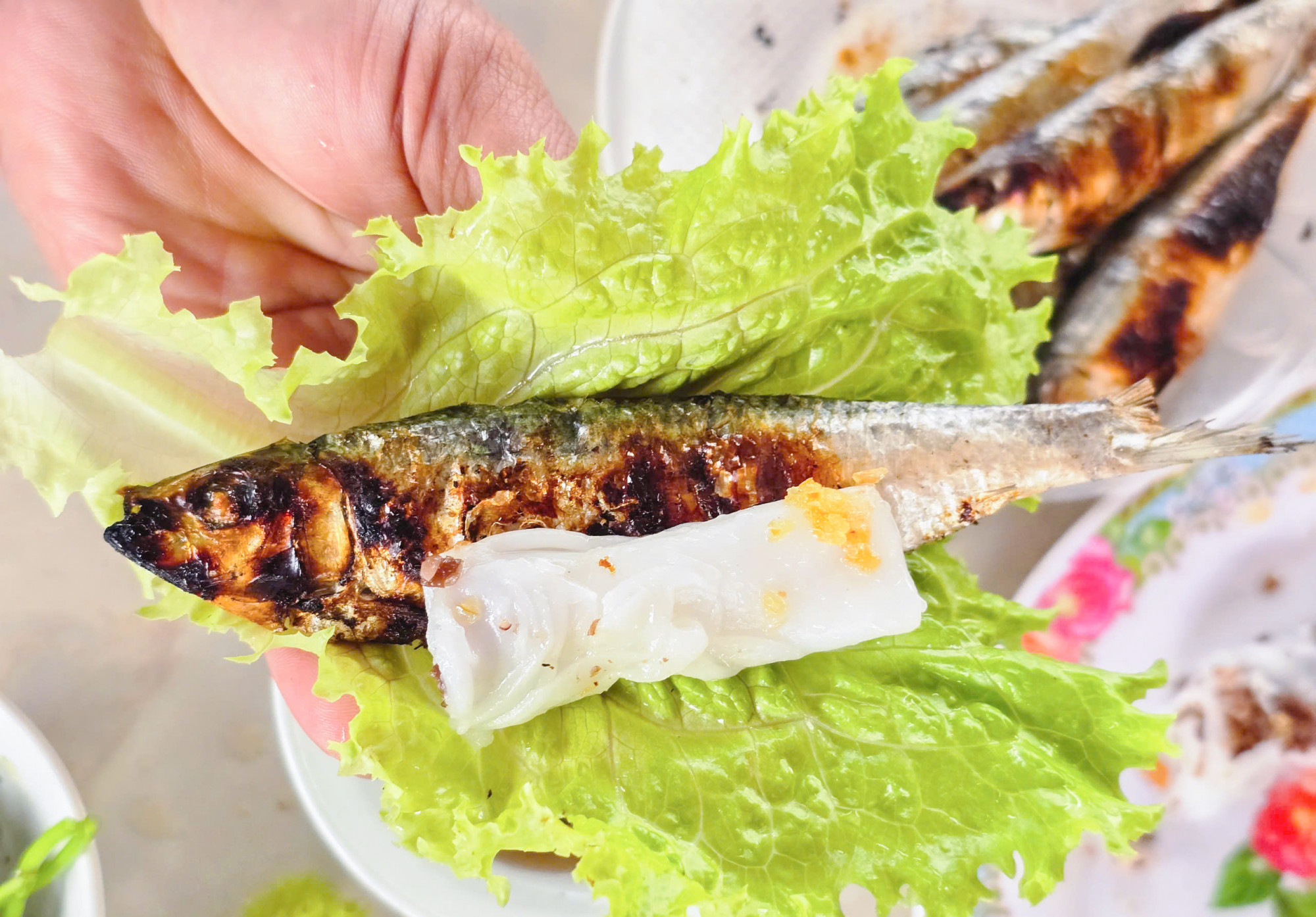 Mỗi lần về với đền Cờn d&acirc;ng hương đều tranh thủ t&igrave;m đến c&aacute;c qu&aacute;n nướng c&aacute; tr&iacute;ch để thưởng thức. &ldquo;C&aacute; tr&iacute;ch sau khi nướng xong c&oacute; thể bỏ xương răm hoặc để nguy&ecirc;n con g&oacute;i c&ugrave;ng c&aacute;c loại rau, b&aacute;nh mướt rồi chấm nước mắm. Khi ăn kết hợp như thế n&agrave;y rất ngon&rdquo; - anh T&igrave;nh n&oacute;i.