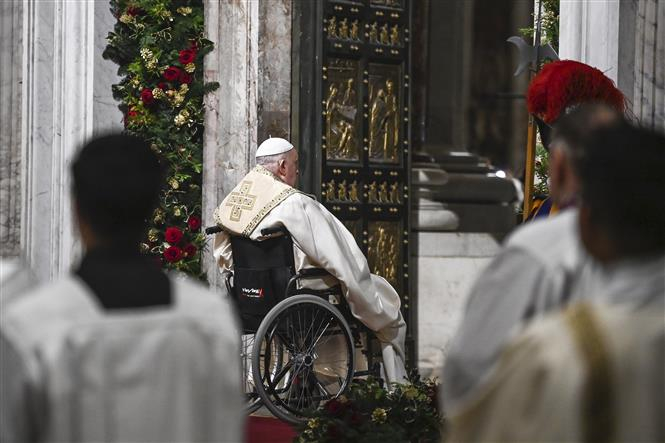 Gi&aacute;o ho&agrave;ng Francis ngồi tr&ecirc;n xe lăn, mở c&aacute;nh cửa khổng lồ bằng đồng mang t&ecirc;n Cửa Th&aacute;nh (Holy Door) tại Vương cung th&aacute;nh đường Th&aacute;nh Peter ở Vatican, đ&aacute;nh dấu bắt đầu Năm Th&aacute;nh 2025. Ảnh: AA/TTXVN