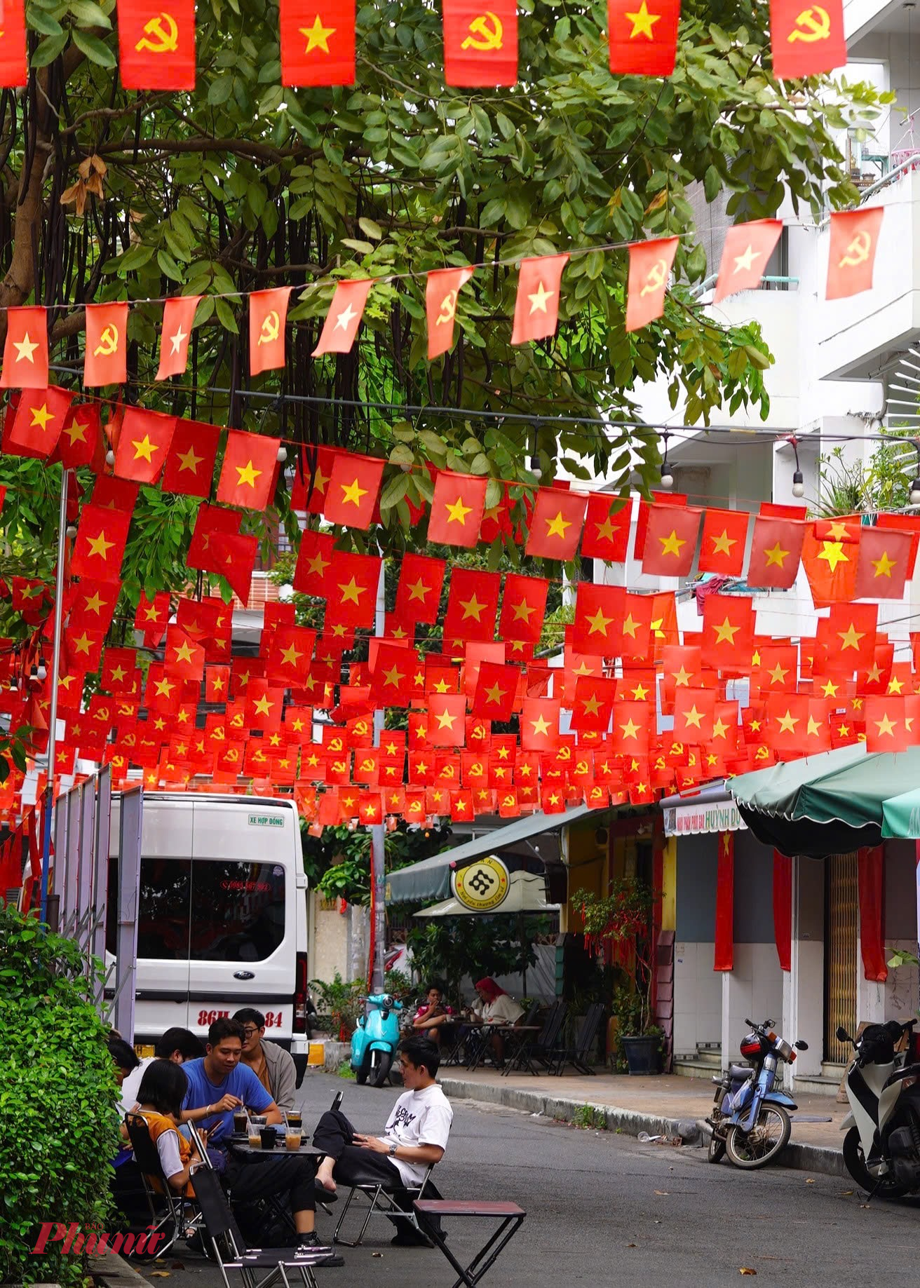 Kh&ocirc;ng gian qu&aacute;n c&agrave; ph&ecirc; ven đường cũng kho&aacute;c l&ecirc;n m&igrave;nh sắc đỏ của ng&agrave;y hội non s&ocirc;ng, h&ograve;a nhịp c&ugrave;ng hơi thở lịch sử - Ảnh: Thanh T&acirc;m