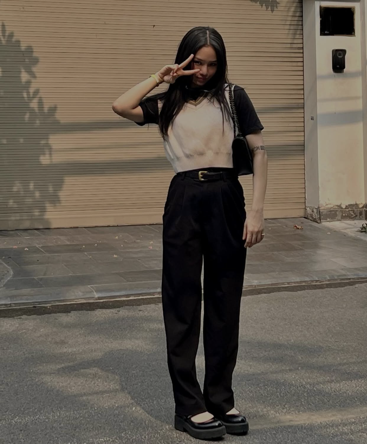 Nữ ca sĩ ghi điểm với phong c&aacute;ch preppy hiện đại với combo &aacute;o thun đen mix c&ugrave;ng &aacute;o len gile trắng, quần ống su&ocirc;ng lưng cao v&agrave; gi&agrave;y Mary Jane. Tổng thể đơn giản nhưng chỉn chu, to&aacute;t l&ecirc;n vẻ trẻ trung v&agrave; tinh nghịch.