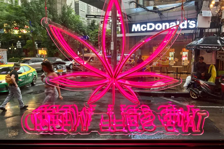 Một biển hiệu h&igrave;nh cần sa bằng đ&egrave;n neon ph&aacute;t s&aacute;ng trong cửa sổ của tiệm thuốc Wonderland ở Bangkok, Th&aacute;i Lan, v&agrave;o ng&agrave;y 28/6/2025 - Ảnh: Zsombor Peter/Al Jazeera