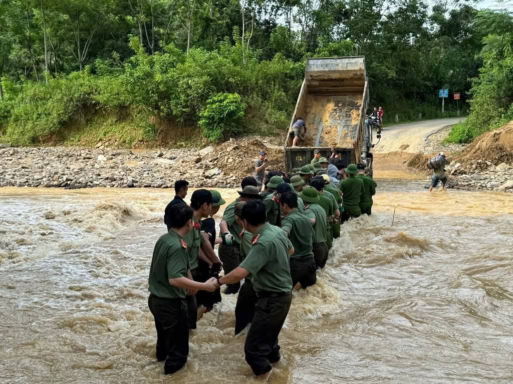 Gần 40 c&ocirc;ng an nắm tay nhau lập h&agrave;ng r&agrave;o sống để đưa sản phụ vượt qua d&ograve;ng nước chảy xiết - Ảnh: Kh&aacute;nh Trung