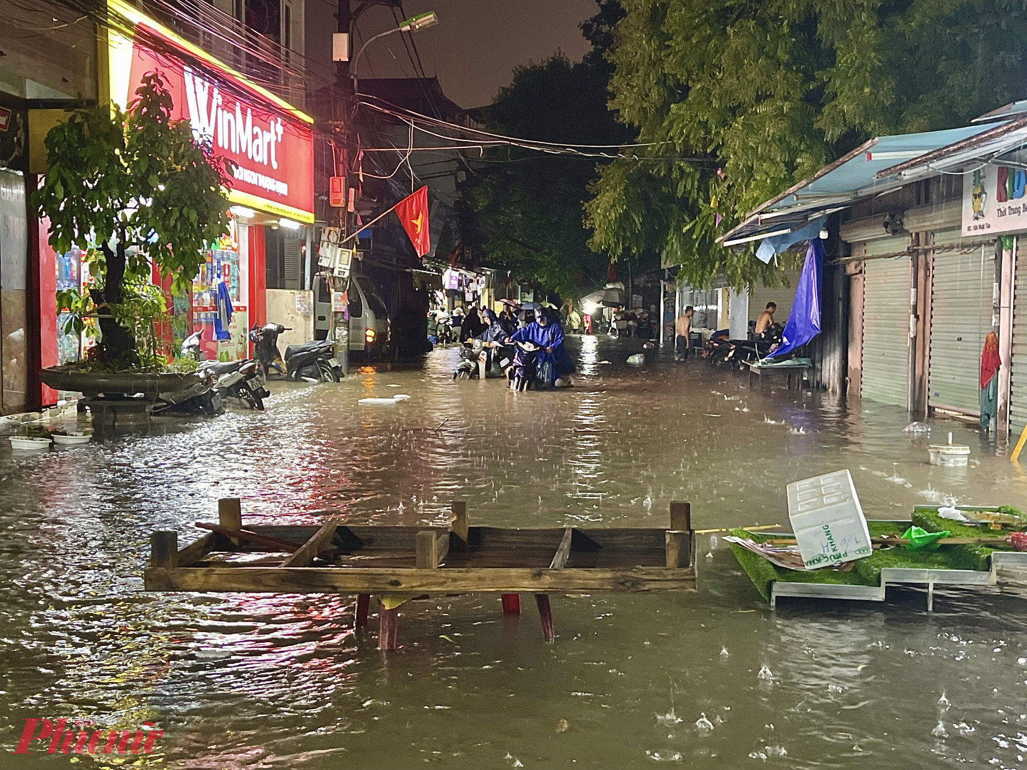 Người d&acirc;n d&ugrave;ng ghế, tấm gỗ,... chắn cảnh b&aacute;o điểm ngập, hạn chế c&aacute;c phương tiện đi v&agrave;o v&ugrave;ng nước s&acirc;u.