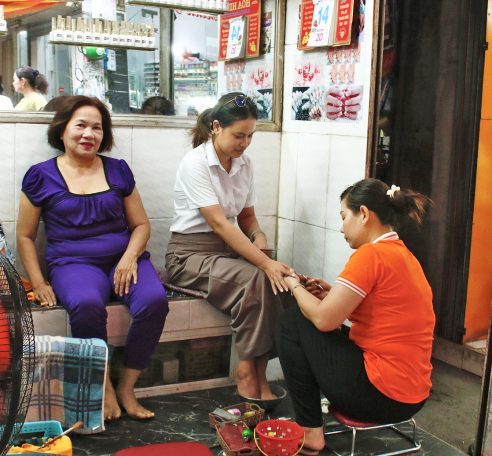 Chị Phạm Thị Bích Đào kiếm thêm thu nhập từ nghề làm móng tại chợ Nhật Tảo - ẢNH: NGỌC TRĂM
