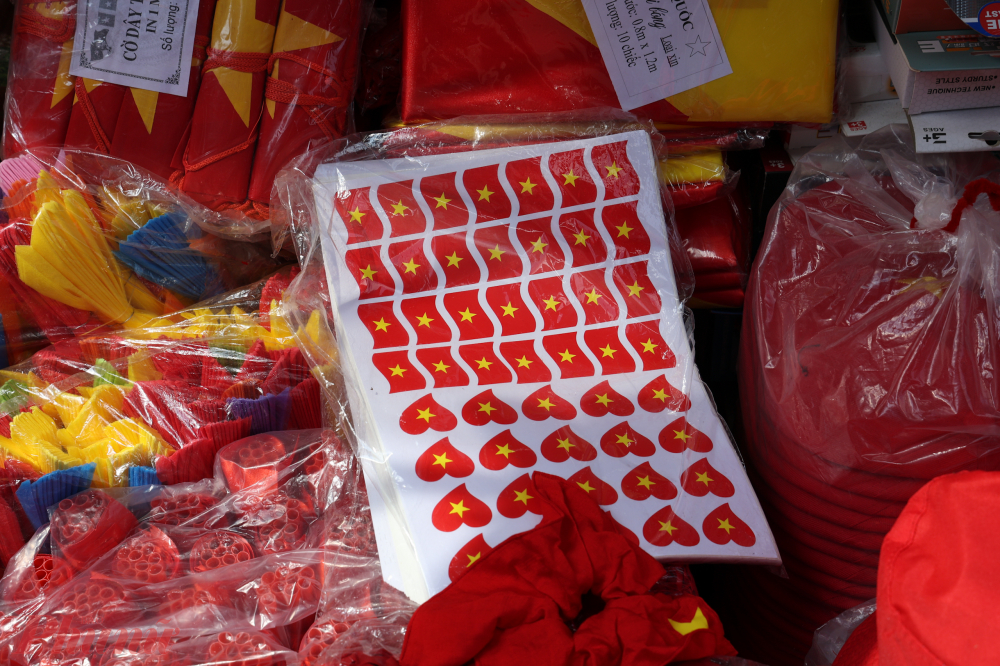 C&aacute;c m&oacute;n đồ trang tr&iacute; từ d&acirc;y kim tuyến, quạt giấy, mũ ch&oacute;p đỏ v&agrave;ng, miếng d&aacute;n sticker&hellip; xếp k&iacute;n trước cửa, mời gọi người qua lại.