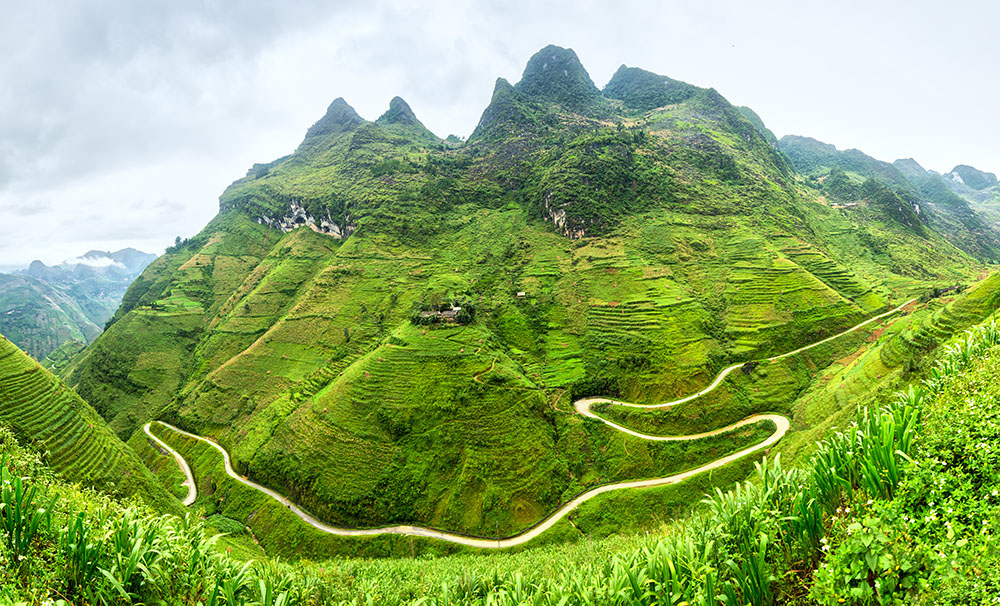 H&agrave; Giang, nơi địa đầu cực Bắc của Việt Nam, sở hữu vẻ đẹp n&uacute;i non v&agrave; ruộng bậc thang kh&ocirc;ng hề k&eacute;m cạnh Sa Pa, nhưng lại vắng b&oacute;ng du kh&aacute;ch trekking hơn nhiều. Phần lớn kh&aacute;ch đến đ&acirc;y chọn chinh phục cung đường đ&egrave;o H&agrave; Giang Loop bằng xe m&aacute;y hoặc &ocirc; t&ocirc; trong 2&ndash;3 ng&agrave;y, men theo những d&atilde;y n&uacute;i h&ugrave;ng vĩ. Thế nhưng, đi bộ mới thật sự gi&uacute;p bạn &ldquo;chạm&rdquo; v&agrave;o cảnh sắc nơi n&agrave;y. Trekking M&atilde; P&iacute; L&egrave;ng mang đến tầm nh&igrave;n ngoạn mục: khi l&agrave;n sương tan dần, hiện ra ng&ocirc;i l&agrave;ng nhỏ dưới thung lũng s&acirc;u; tia nắng lọt qua m&acirc;y rọi xuống người n&ocirc;ng d&acirc;n đội n&oacute;n l&aacute; đang c&agrave;y cấy tr&ecirc;n những thửa ruộng bậc thang. Đỉnh đ&egrave;o, chạm tới bằng con đường m&ograve;n tr&ecirc;n trời chỉ mất khoảng hai giờ đi bộ, mở ra khung cảnh h&ugrave;ng tr&aacute;ng: n&uacute;i rừng trập tr&ugrave;ng, những ngọn n&uacute;i rừng phủ xanh sừng sững, dưới ch&acirc;n l&agrave; d&ograve;ng Nho Quế uốn lượn như dải lụa. Bạn c&oacute; thể chọn cung đường n&agrave;y như một trải nghiệm nhỏ trong h&agrave;nh tr&igrave;nh H&agrave; Giang Loop, hoặc kết hợp th&agrave;nh chuyến trekking nhiều ng&agrave;y để thật sự rời xa d&ograve;ng kh&aacute;ch ba l&ocirc;, h&ograve;a m&igrave;nh v&agrave;o đời sống văn h&oacute;a của người H&rsquo;M&ocirc;ng, người T&agrave;y nơi miền bi&ecirc;n viễn - Ảnh: Wanderlust