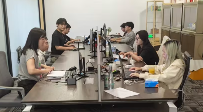 Người d&ugrave;ng trẻ tuổi l&agrave;m việc tại b&agrave;n l&agrave;m việc chung b&ecirc;n trong C&ocirc;ng ty giả vờ l&agrave;m việc kh&ocirc;ng giới hạn H&agrave;ng Ch&acirc;u, một kh&ocirc;ng gian văn ph&ograve;ng giả cung cấp th&oacute;i quen v&agrave; cấu tr&uacute;c trong trường hợp kh&ocirc;ng c&oacute; việc l&agrave;m ch&iacute;nh thức. (Ảnh: C&ocirc;ng ty giả vờ l&agrave;m việc kh&ocirc;ng giới hạn H&agrave;ng Ch&acirc;u)