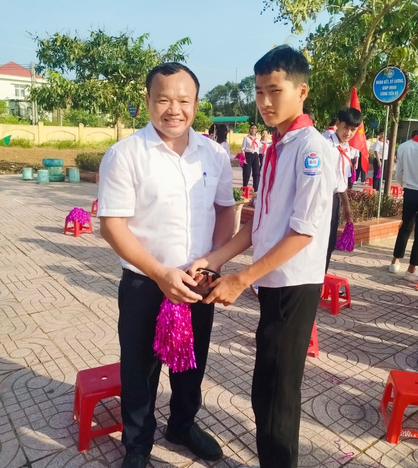 &Ocirc;ng Nguyễn Xu&acirc;n Kh&aacute;nh, Ph&oacute; B&iacute; thư Thường trực Đảng ủy x&atilde; B&iacute;ch H&agrave;o th&aacute;o d&acirc;y thắt lưng tặng học sinh lớp 8 sau lễ khai giảng năm học mới. Ảnh: Trần Đ&igrave;nh Thơ.