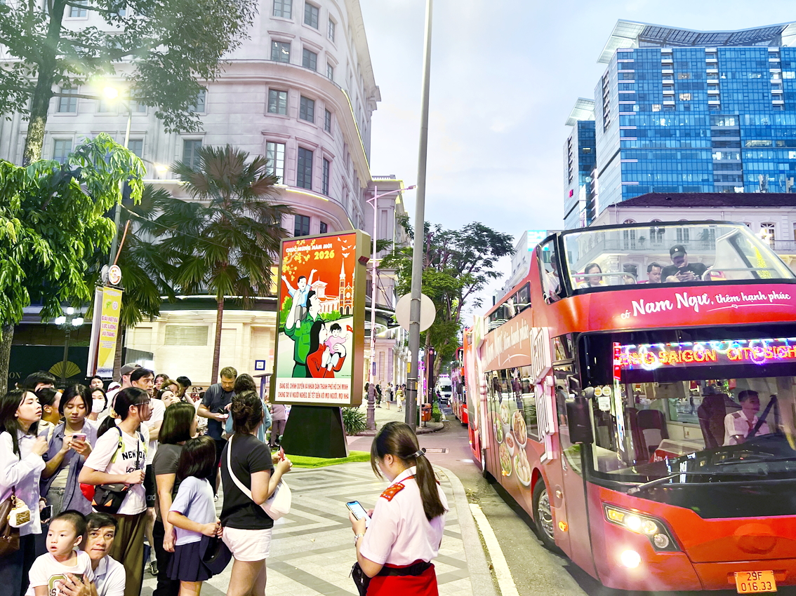 Đo&agrave;n du kh&aacute;ch chuẩn bị l&ecirc;n buýt 2 tầng tham quan trung t&acirc;m TPHCM đêm Giáng sinh 2025 - ẢNH: QUỐC TH&Aacute;I