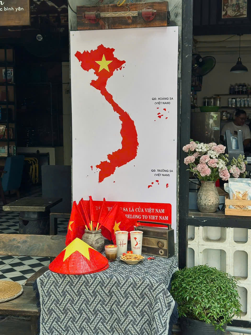 Ngay từ những ng&agrave;y đầu th&aacute;ng 4, Tiệm c&agrave; ph&ecirc; Han (1162 Phạm Văn Đồng, phường Thủ Đức)đ&atilde; phủ kh&ocirc;ng gian bằng cờ đỏ sao v&agrave;ng c&ugrave;ng sạp b&aacute;o nhỏ v&agrave; poster &ldquo;Tuy&ecirc;n ng&ocirc;n Độc lập&rdquo;, tạo n&ecirc;n background độc đ&aacute;o cho kh&aacute;ch chụp ảnh.