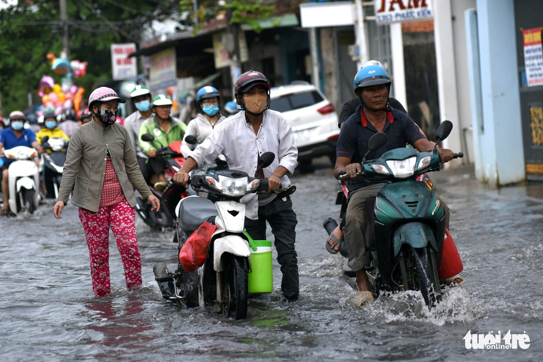 Triều cường dâng cao, học sinh, công nhân ở TP.HCM lội nước về nhà - Ảnh 4.