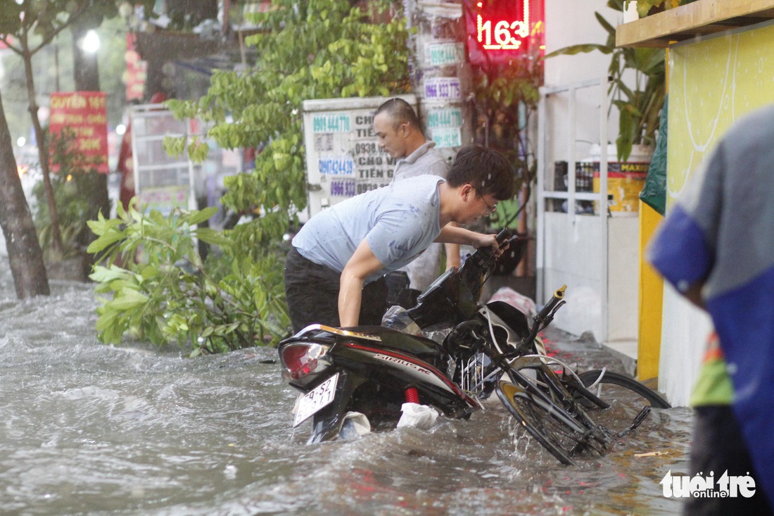 TP.HCM mưa gió mù mịt 2 tiếng: đường ngập khắp nơi, cây đổ, xe ngã... - Ảnh 2.