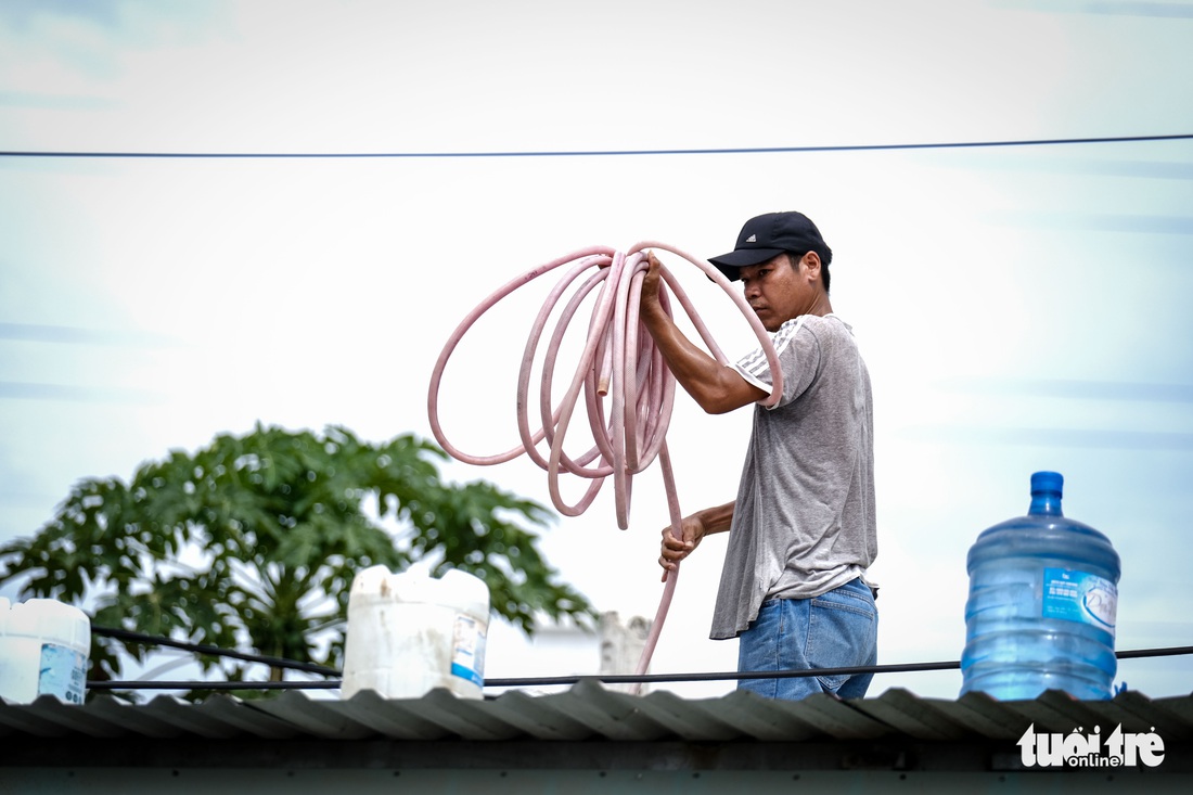 Người dân cột các thùng nước trên mái nhà để phòng tránh bão - Ảnh 1.