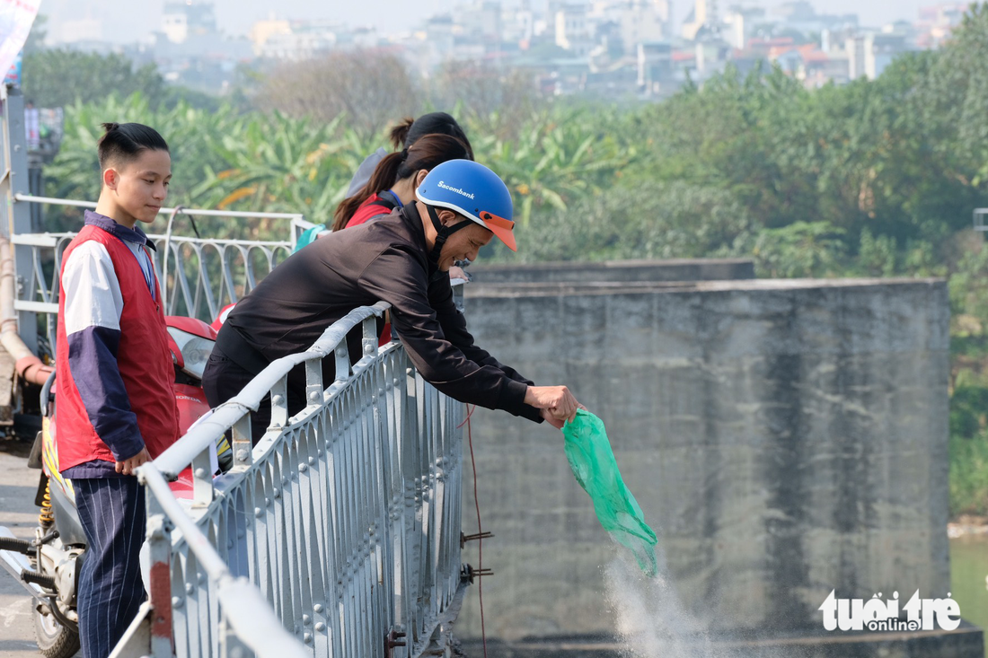 Thả cá, rải tro cúng ông Công ông Táo, bao rác kề bên vẫn ném túi ni lông xuống mặt đường - Ảnh 1.