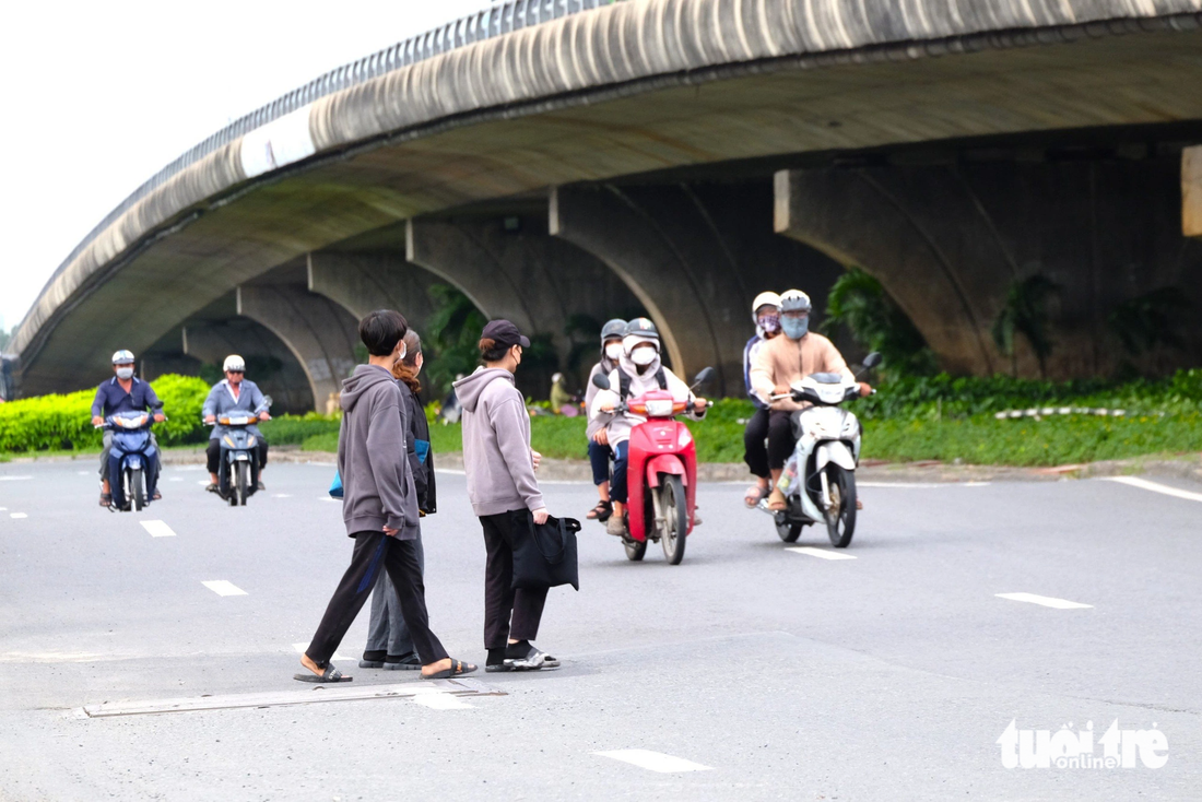 Ngược lại, bên trên hầm chui, dòng người băng ngang sang đường tấp nập. Hầu hết người dân băng ngang qua quốc lộ 1 đông nghẹt xe tải, mặc kệ dòng xe tải bấm còi inh ỏi. Trong khi đó, khu vực giao lộ này là một trong những điểm đen liên tục xảy ra tai nạn giao thông. Giờ tan tầm, nhiều công nhân đi thành đoàn, giơ tay xin đường.