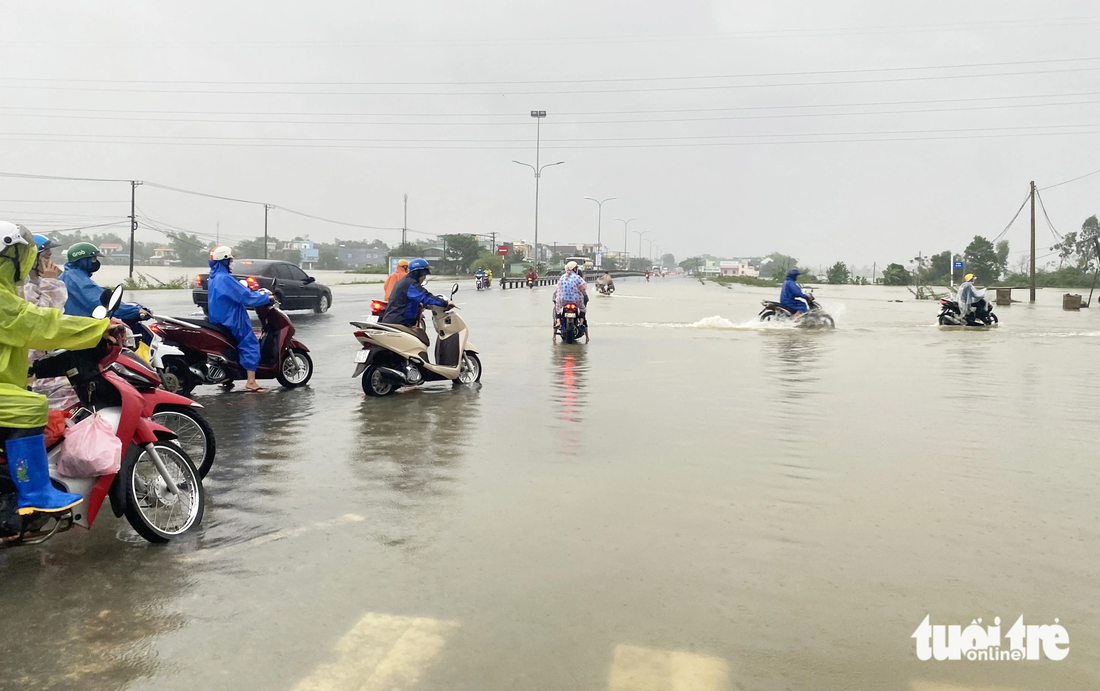 Công nhân Khu công nghiệp Tam Thăng dắt xe qua đoạn ngập - Ảnh: LÊ TRUNG