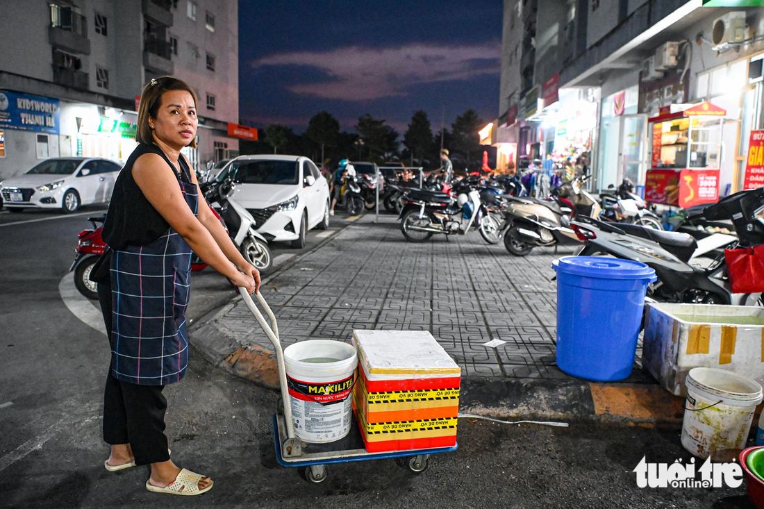 Bị cắt nước không chỉ ảnh hưởng tới sinh hoạt của cư dân mà những hộ kinh doanh cũng chịu thiệt hại nặng nề. Họ phải đi chở từng xô nước về cửa hàng - Ảnh: HỒNG QUANG