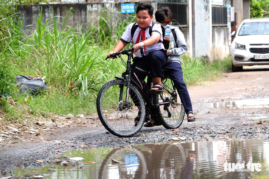 Hai học sinh loạng choạng né &quot;ổ gà&quot; trên đường Giác Đạo (xã Trung Chánh, huyện Hóc Môn) - Ảnh: PHƯƠNG NHI