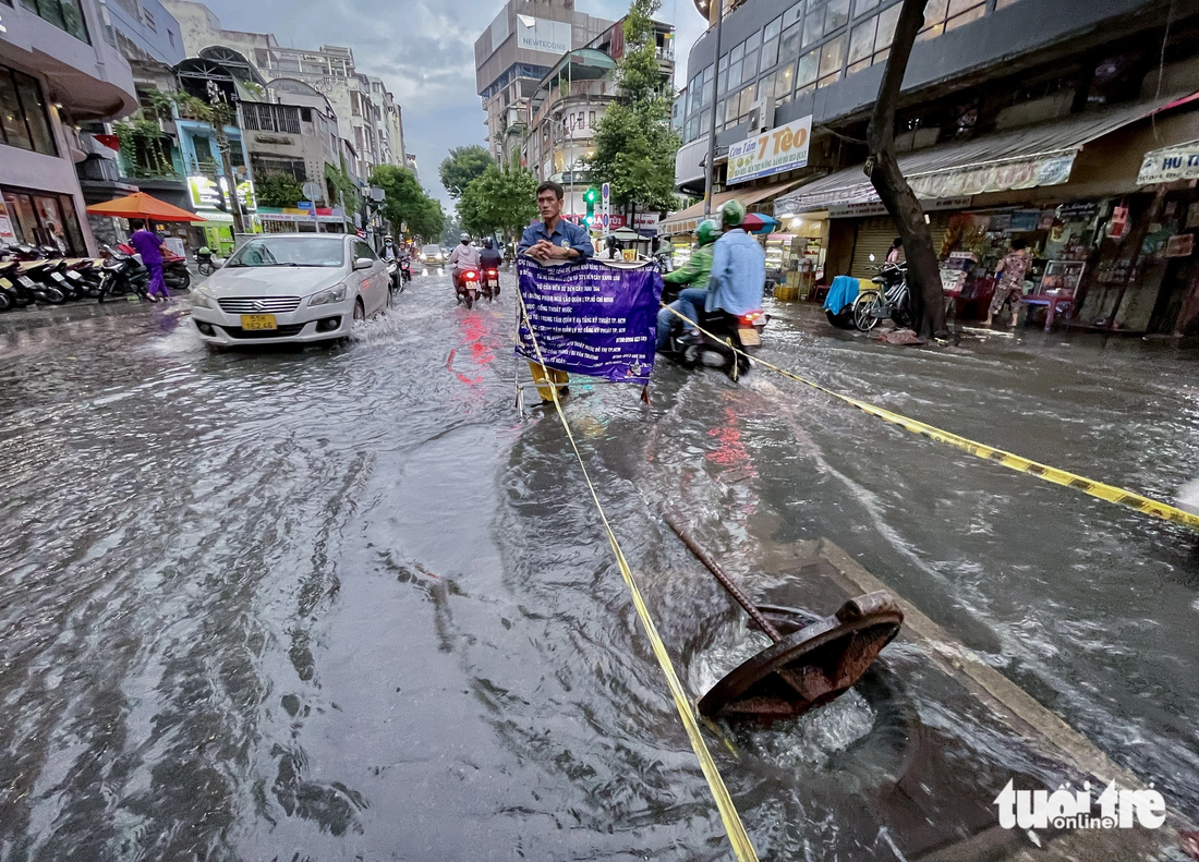 Nhân viên thoát nước đô thị phải bật tung nắp cống đường Calmette (quận 1, TP.HCM) để giảm ngập do triều cường - Ảnh: CHÂU TUẤN