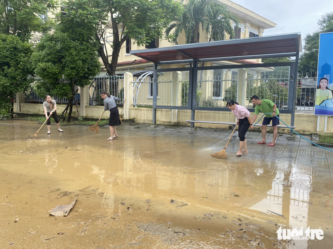 Nhân viên một trụ sở nhà nước dọn vệ sinh sau khi lũ rút - Ảnh: LÊ TRUNG