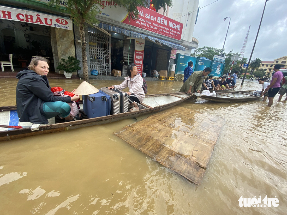 Dùng ghe thuyền đưa khách du lịch ra khỏi vùng ngập lũ - Ảnh: LÊ TRUNG