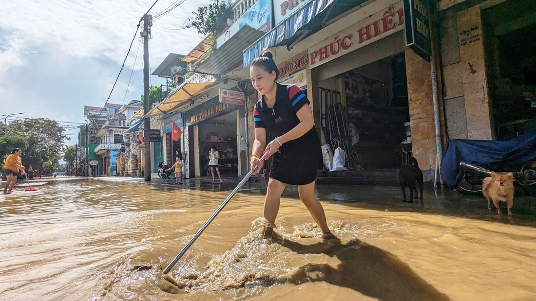 Chị Phúc Hiền (trú Huỳnh Thúc Kháng, TP Huế) vừa dọn lũ, vừa thấp thỏm nỗi lo tái ngập vì mưa lớn - Ảnh: NHẬT LINH