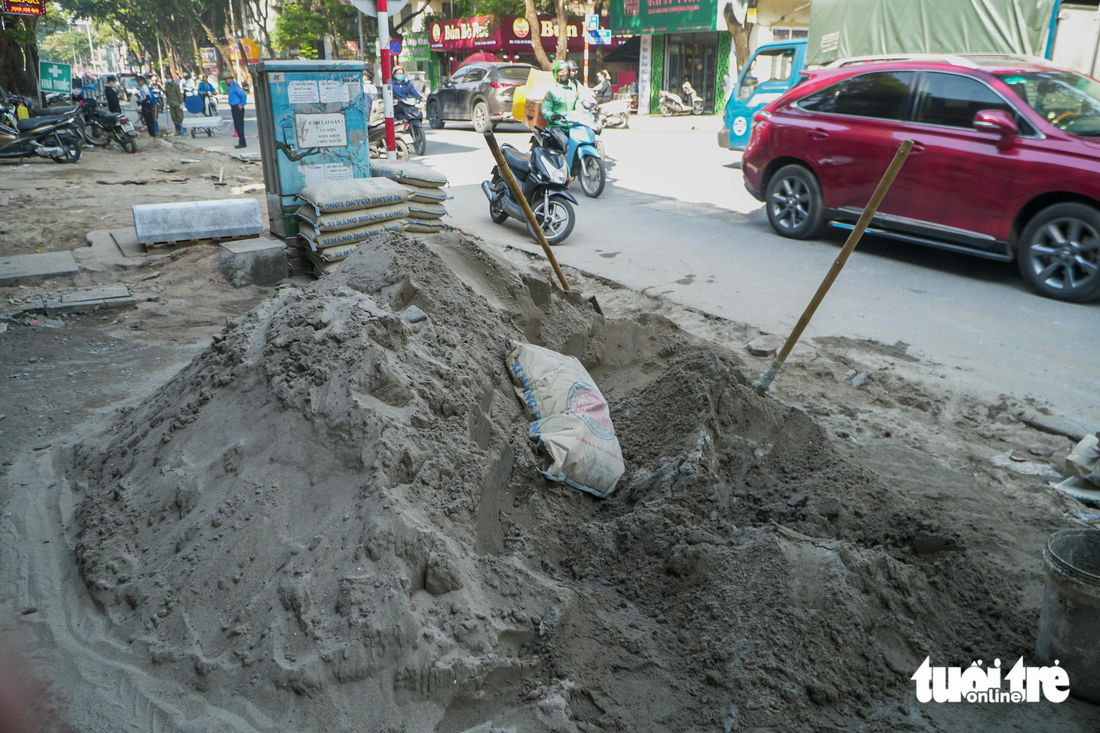 Những đống xi măng trộn cát lớn trên vỉa hè cản trở việc đi lại của người dân - Ảnh: PHẠM TUẤN