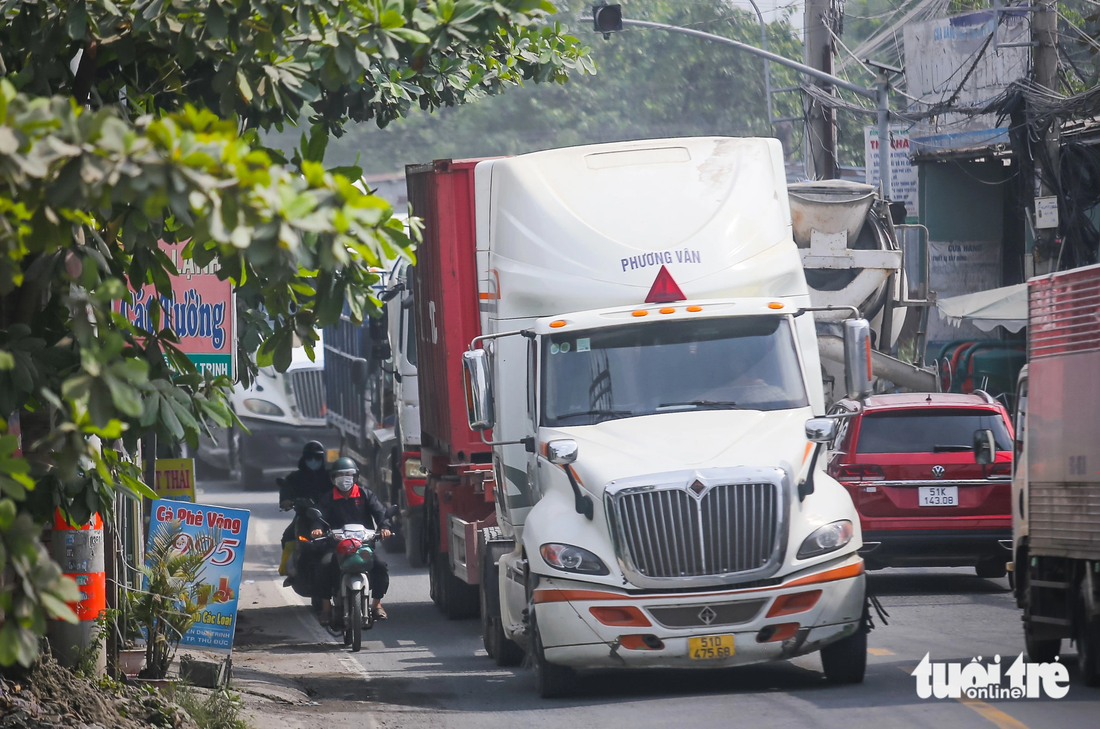 Xe máy, xe đạp chỉ còn khoảng nửa mét đường sát vỉa hè để đi. Chạy sát bên những &quot;gã khổng lồ&quot;, ai cũng nơm nớp, tai nạn có thể xảy ra bất cứ lúc nào - Ảnh: LÊ PHAN