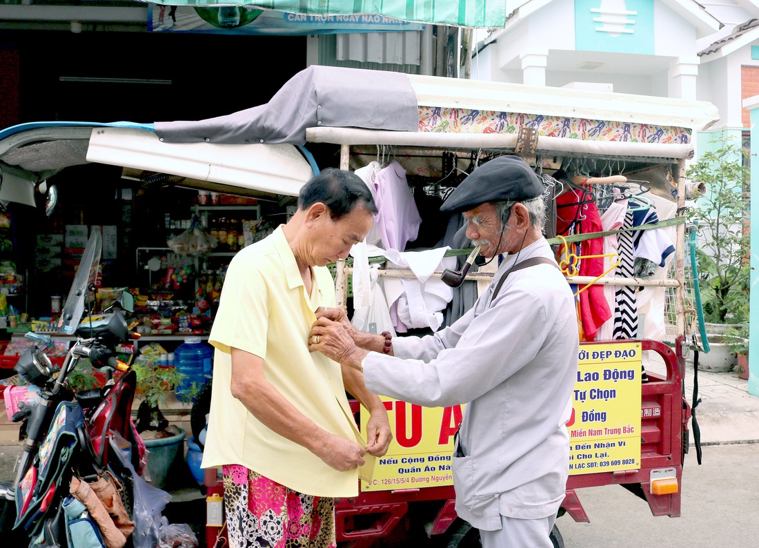 Ông Tư Ẩn giúp một người ướm thử chiếc áo mới ngay tại gian hàng 0 đồng