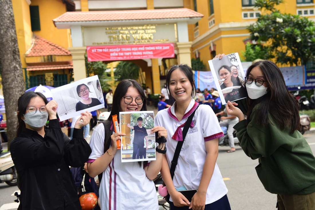 Hai bạn Uyên Khanh và Ngọc Mai được bạn cổ vũ khi đi làm thủ tục dự thi tại điểm thi THPT Trưng Vương, TP.HCM  - Ảnh: DUYÊN PHAN