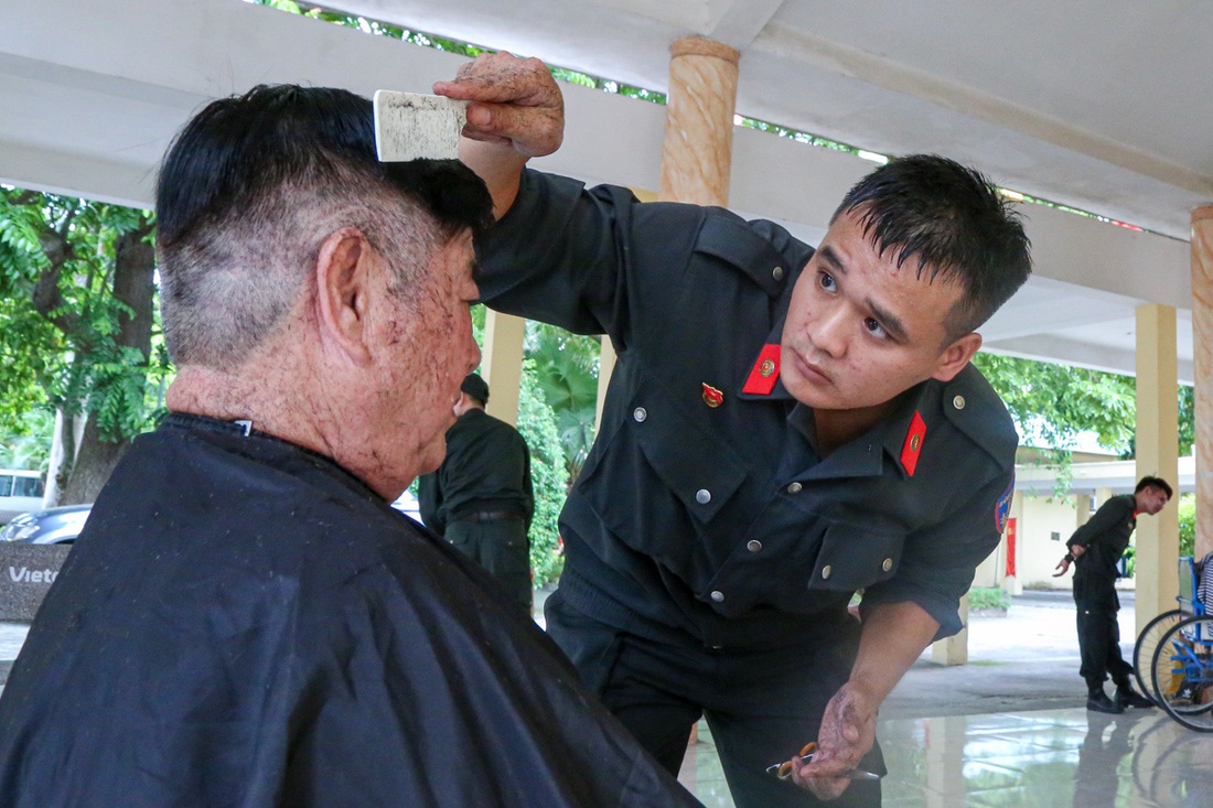 Trung úy cảnh sát cơ động Hoàng Anh mướt mồ hôi khi tạo kiểu cho các bác thương binh, vì sợ &quot;cắt xấu các bác trừ điểm&quot; - Ảnh: HÀ QUÂN