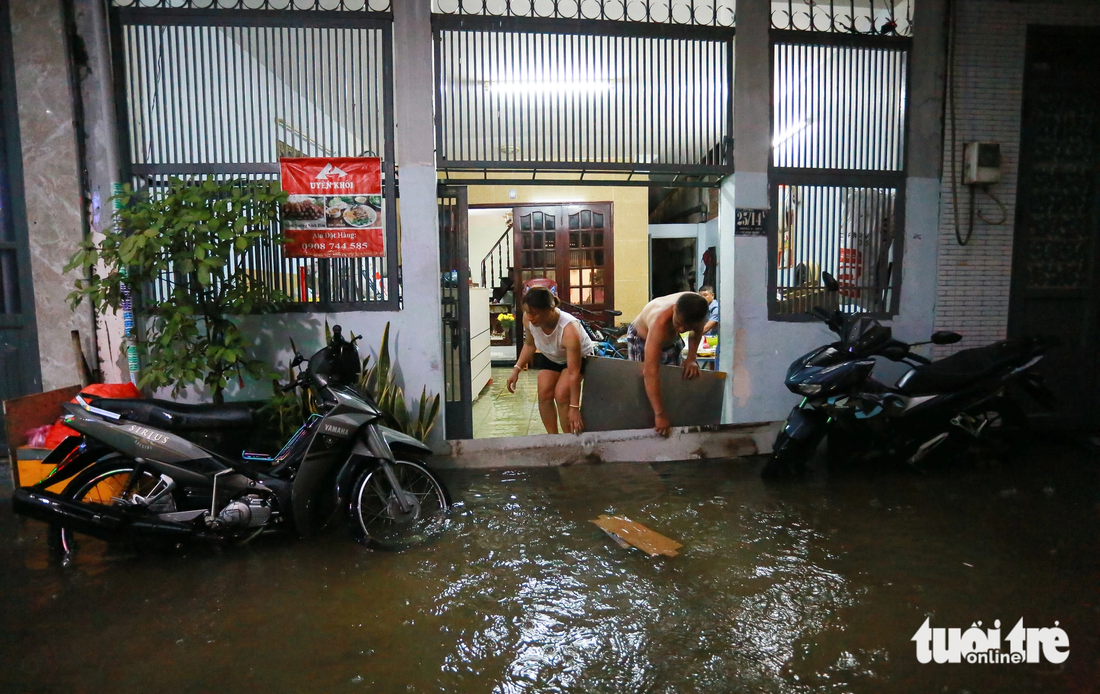 Người dân phải &quot;đắp đê&quot; ngăn nước tràn vào nhà. Ghi nhận trên đường số 6 (từ quốc lộ 13 chạy vào khoảng 200m, thuộc phường Hiệp Bình Phước, TP Thủ Đức) - Ảnh: CHÂU TUẤN