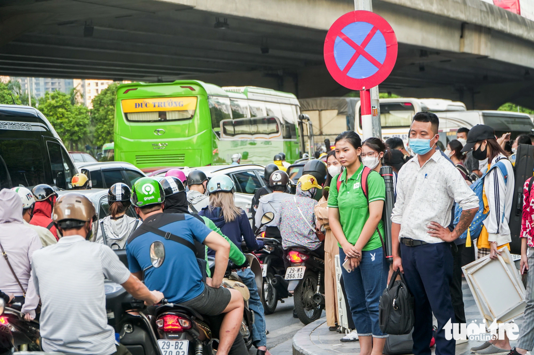 Nhiều người dân &quot;tay xách nách mang&quot; ra cạnh vỉa hè đợi để bắt xe về quê - Ảnh&quot; PHẠM TUẤN