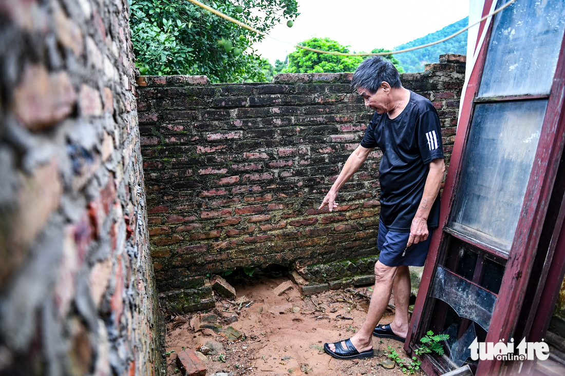 Nhưng nước chảy quá mạnh, kéo theo đất đá từ đồi cao nên sợ sập nhà, ông phải đập các lỗ ở tường để thoát nước - Ảnh: NAM TRẦN